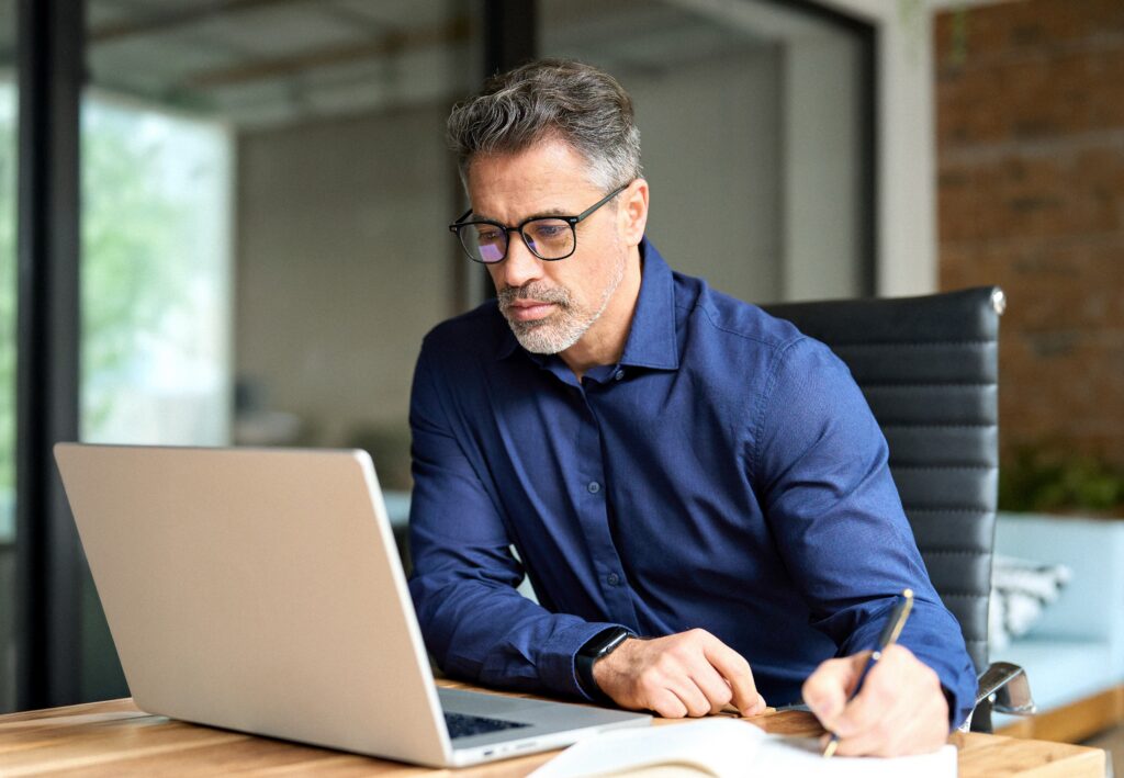 business owner writing on paper and looking at computer